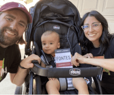 Two Arizona voters with a baby holding Adrian Fontes lit.