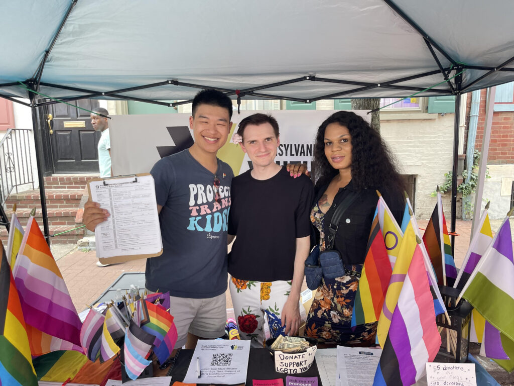 OutVote co-founder Ranen Miao stands for a photo with two volunteers. They are registering voters for a pride event.