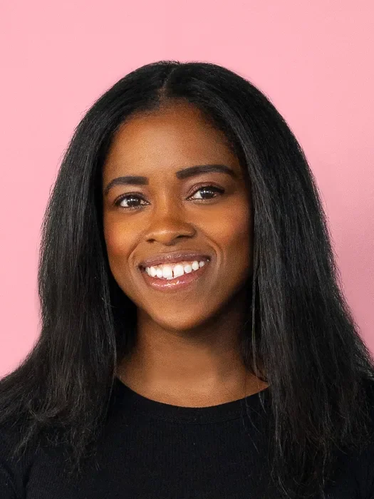 A photo of Shaniqua McClendon smiling against a light pink background. 